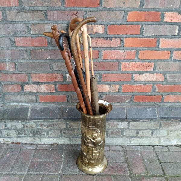 Vintage brass stick and umbrella stand with collection of walking sticks.