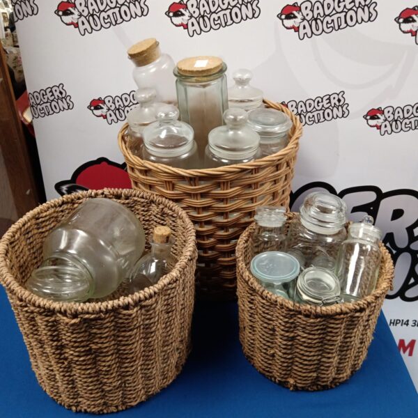 Three woven baskets filled with assorted vintage glass jars.