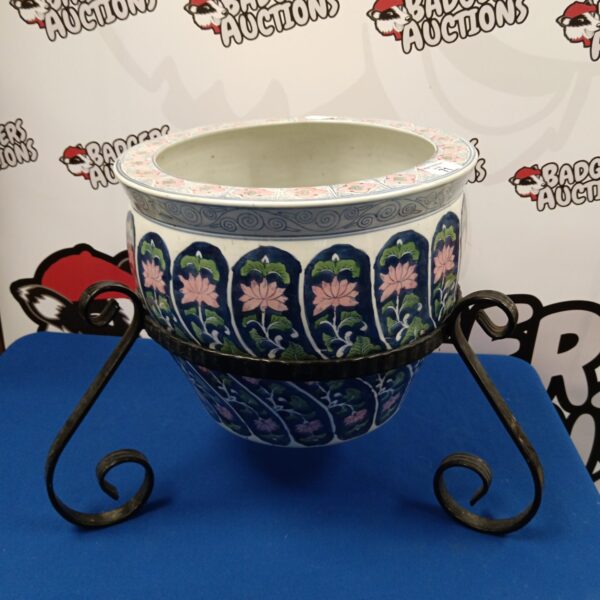 Vintage ceramic floral planter with wrought iron stand for garden decor.