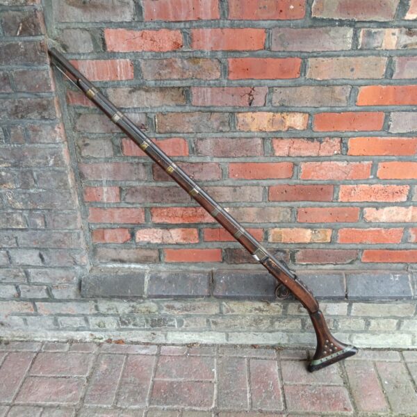 Vintage Indian musket with detailed wood carving and metal accents.