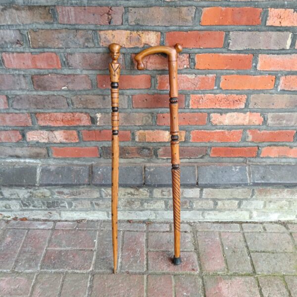 Pair of intricately carved African walking sticks displayed indoors.