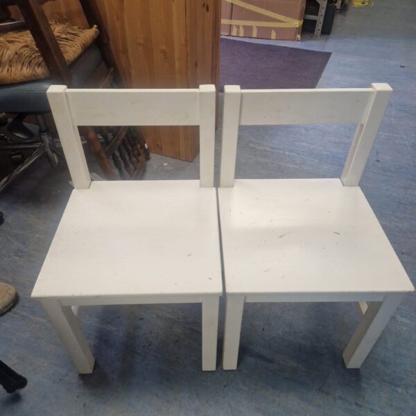 Two white wooden children’s chairs for playroom use.
