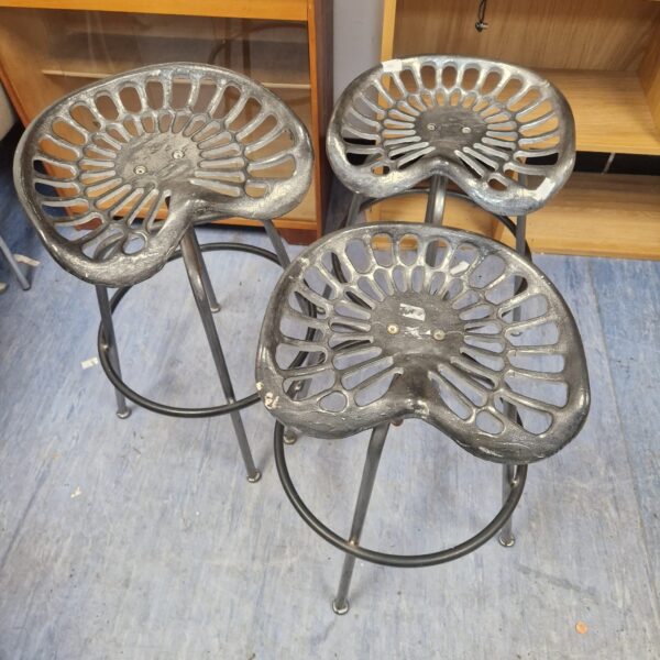 Lot of three vintage tractor seat stools with metal legs.