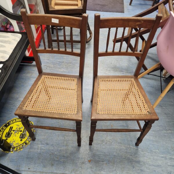Pair of vintage wooden chairs with rattan seats.