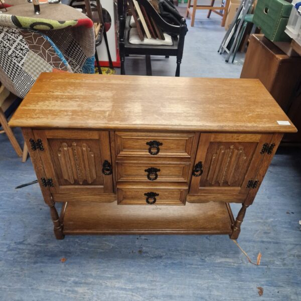 Vintage oak side cabinet with three drawers and open shelf.