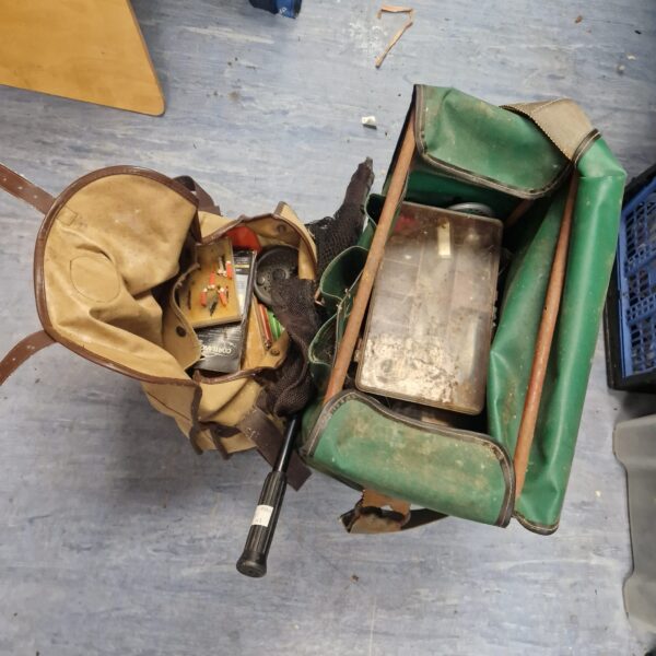 Vintage fishing bag filled with tackle and reels.
