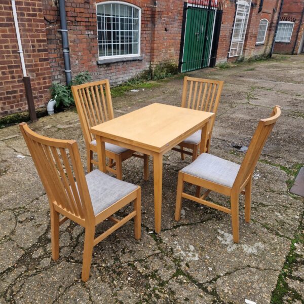 Ikea dining set with wooden table and grey chairs.