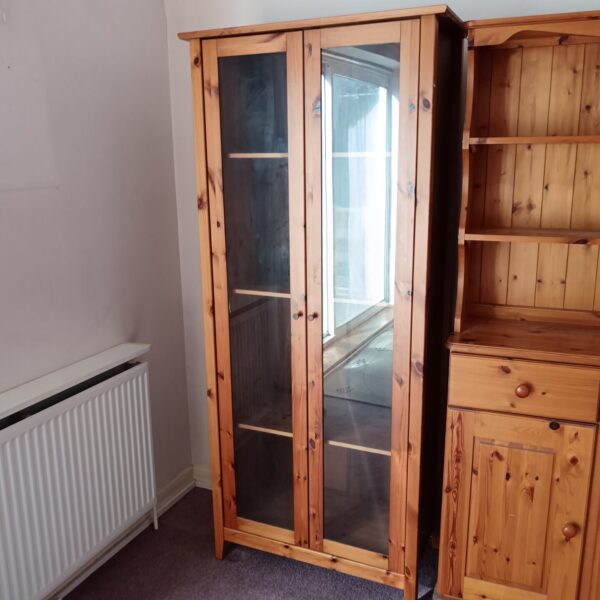 Vintage pine display cabinet with glass doors and shelving.