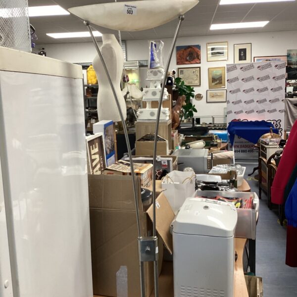 Chrome standard lamp in a cluttered room setting.