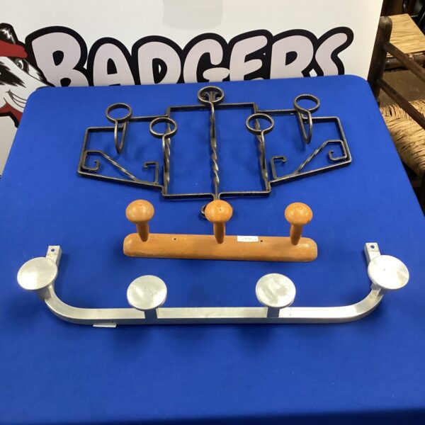 Three vintage iron coat hooks mounted on a wall.