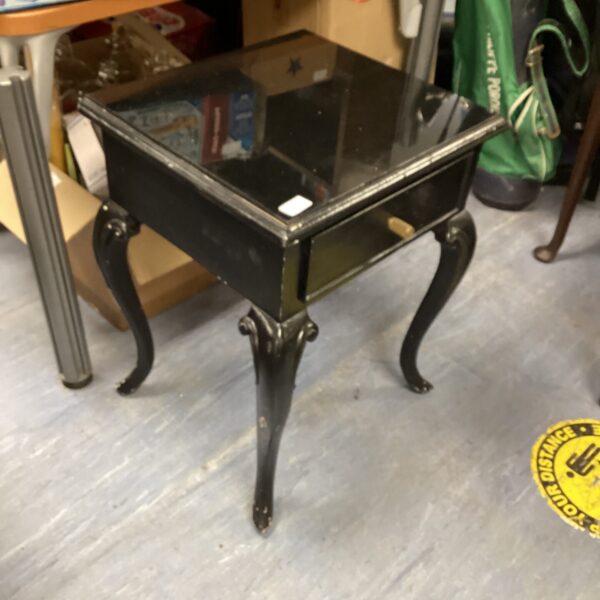 Vintage black occasional table with glass top and curved legs.