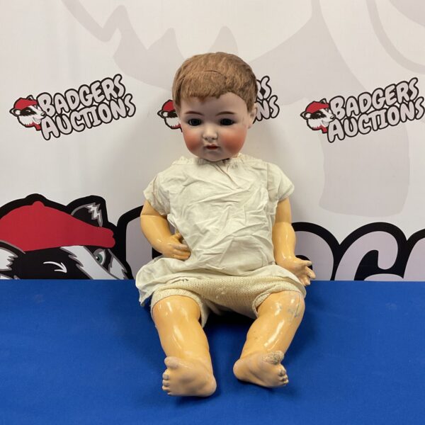 Antique porcelain doll with painted features and vintage clothing.