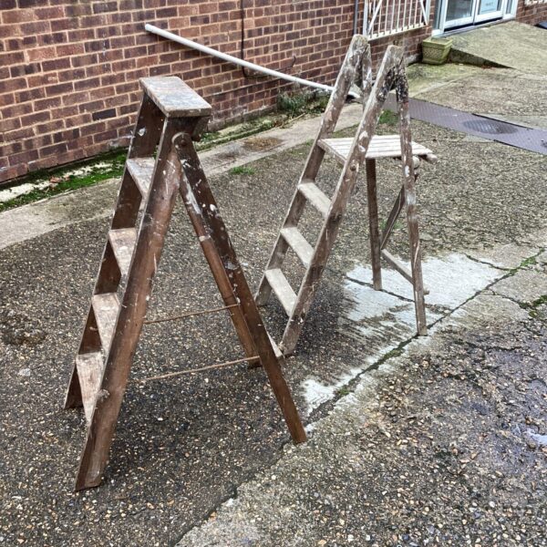 Pair of vintage wooden step ladders in a garden setting.