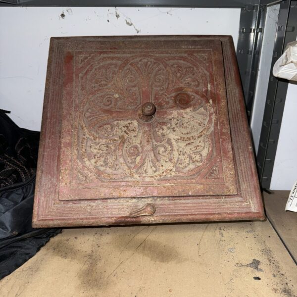 Intricate antique cast iron chimney vent for fireplace restoration.