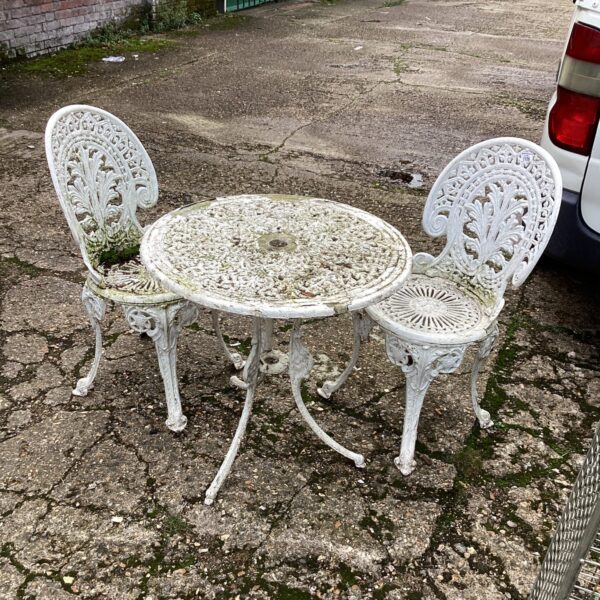 Vintage metal garden set with floral detailing in a garden setting.