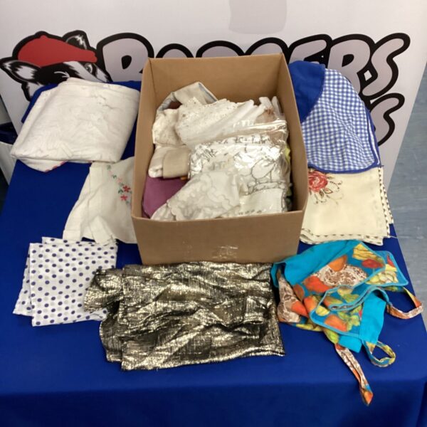 Overview of a vintage linen lot with embroidered tablecloths and doilies.