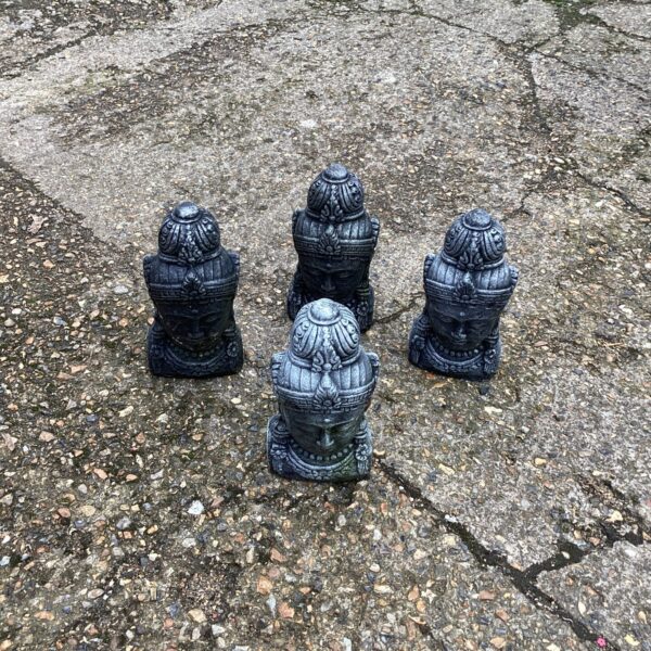 Four antique stone Buddha heads sculpture, serene religious art.