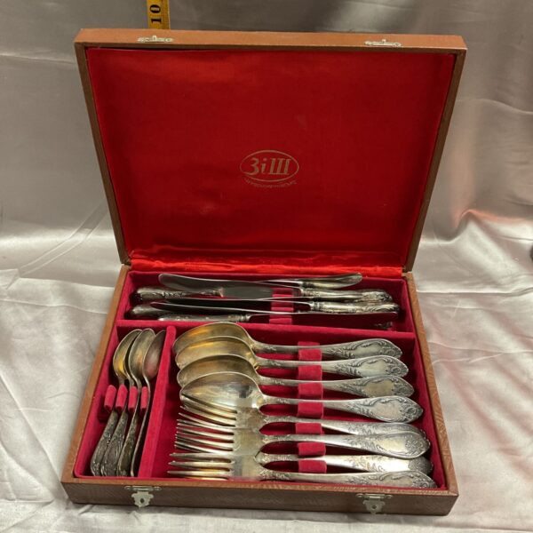 Open wooden case displaying a vintage Russian whitemetal cutlery set.