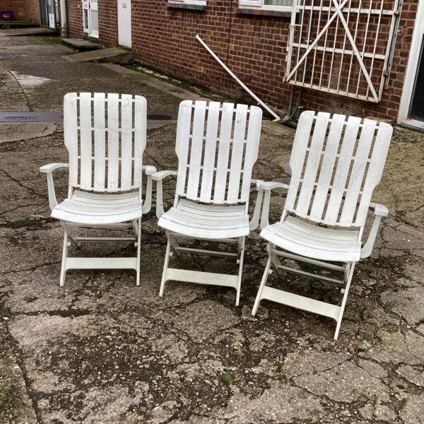 Set of three plastic garden chairs in a garden setting.