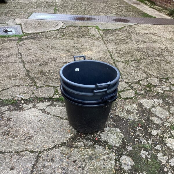 Three black plastic garden planters stacked outdoors.