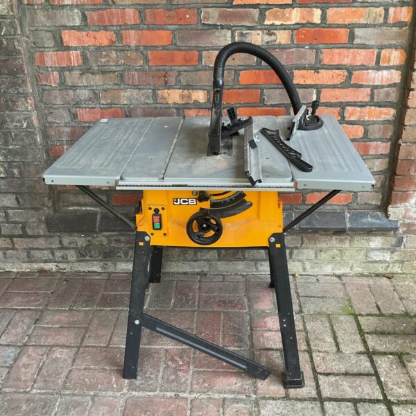Front view of a JCB table saw on a brick background.