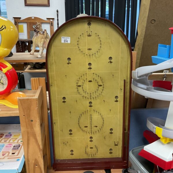 Vintage bagatelle game with wooden playing field and pins.