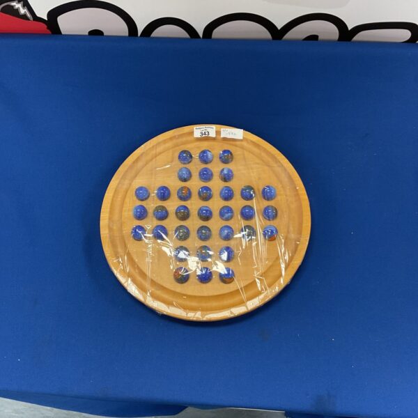 Vintage wooden solitaire game with blue marbles on display.