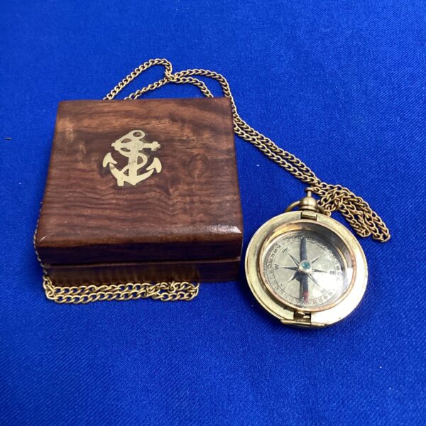 Antique brass pocket compass in a wooden box, vintage nautical instrument.