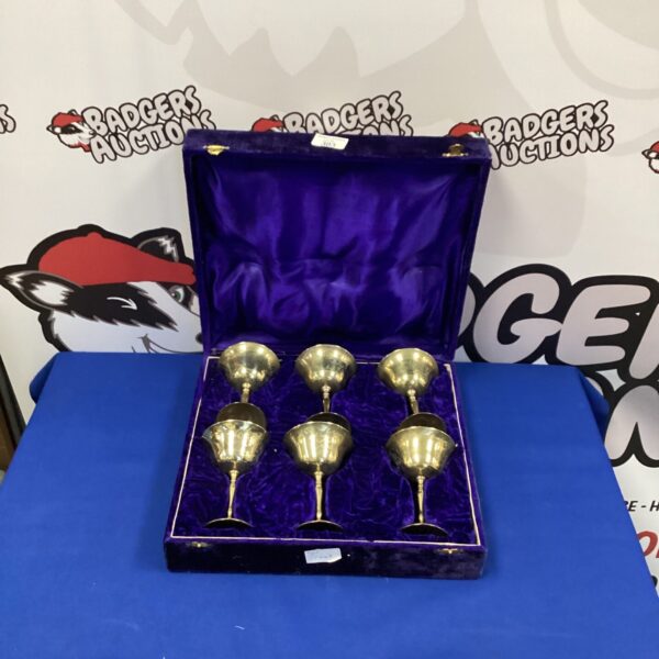 Six vintage brass wine goblets displayed in a presentation case.