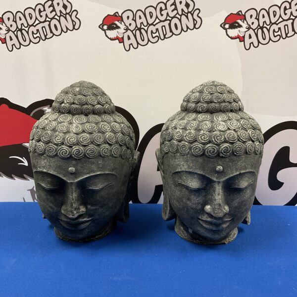 Pair of weathered cast stone Buddha heads for garden display.