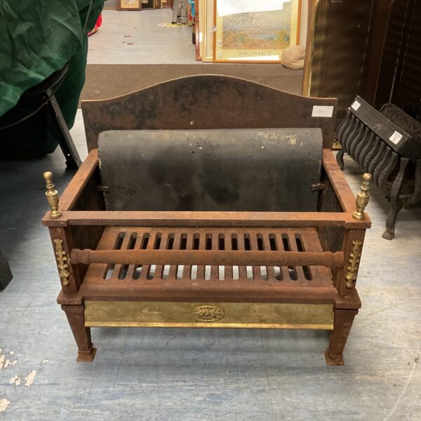 Antique wrought iron fire grate with brass finials for a fireplace hearth.
