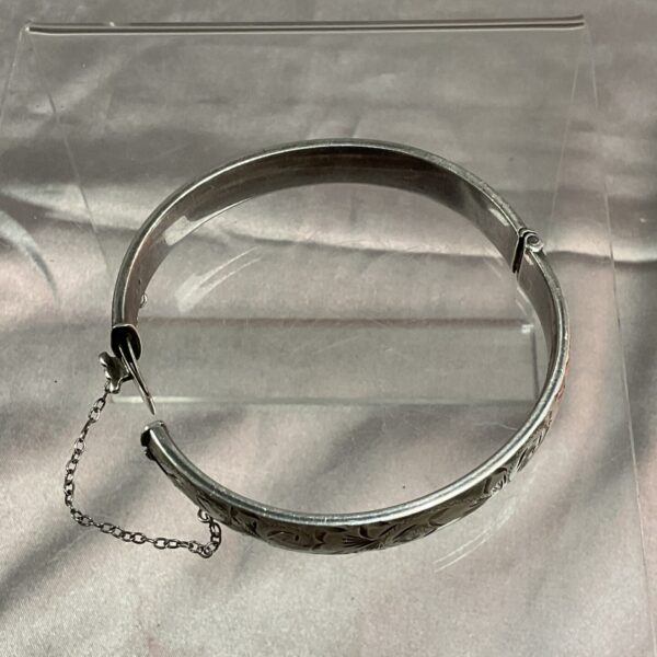 Intricate antique silver hinged bracelet with embossed floral details.