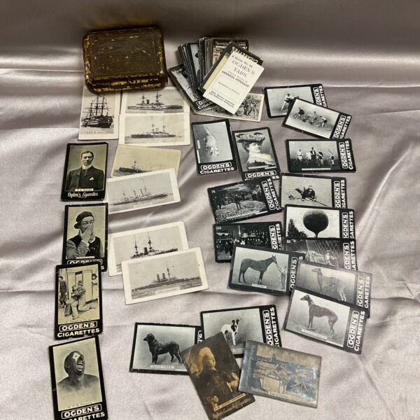 Vintage tin filled with collectible Ogdens cigarette cards.