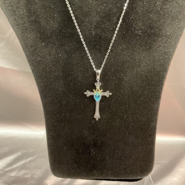 Close-up of 925 silver cross pendant with blue stone.