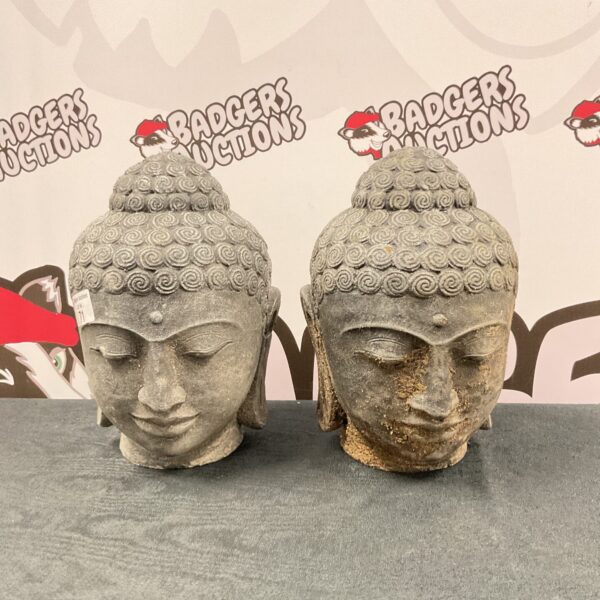 Pair of weathered cast stone Buddha heads for garden display.