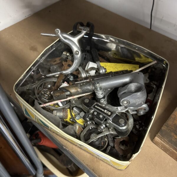 Vintage Shimano cycling parts in a metal tin.