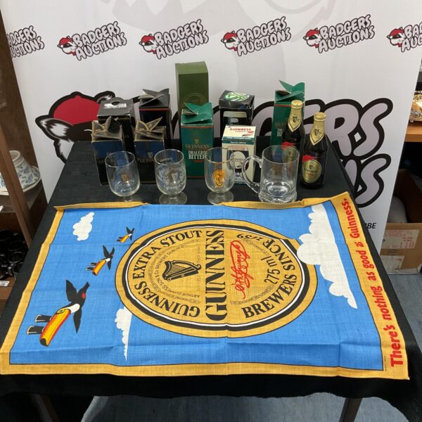 Collection of Guinness glasses and a teatowel on a table.