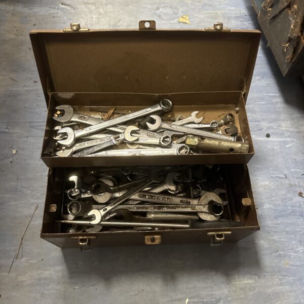 Vintage metal toolbox filled with antique wrenches and tools.