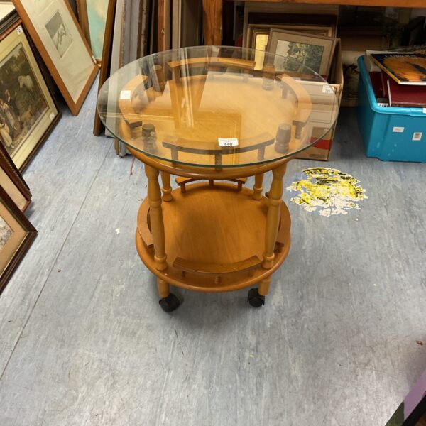 Vintage rolling drink table with glass tiers and wooden frame.