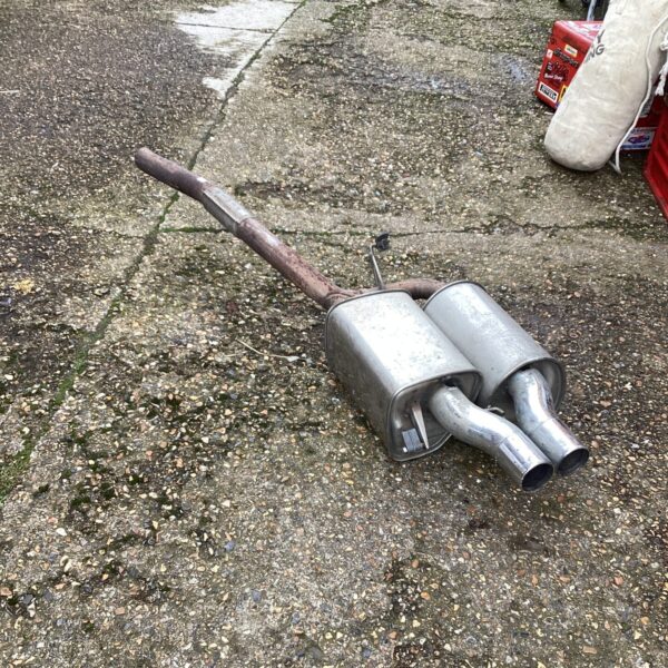 Large vintage exhaust pipe with dual outlets for car restoration.
