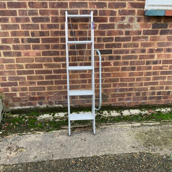Silver aluminium loft ladder leaning against a brick wall.