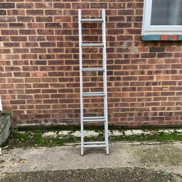 Silver aluminium extending ladder leaning against a wall.