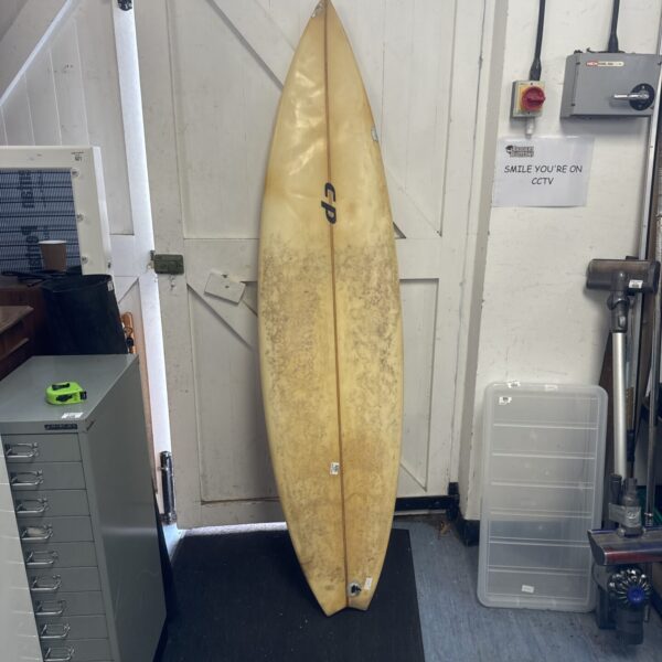 Full view of a vintage CP surfboard in a garage.