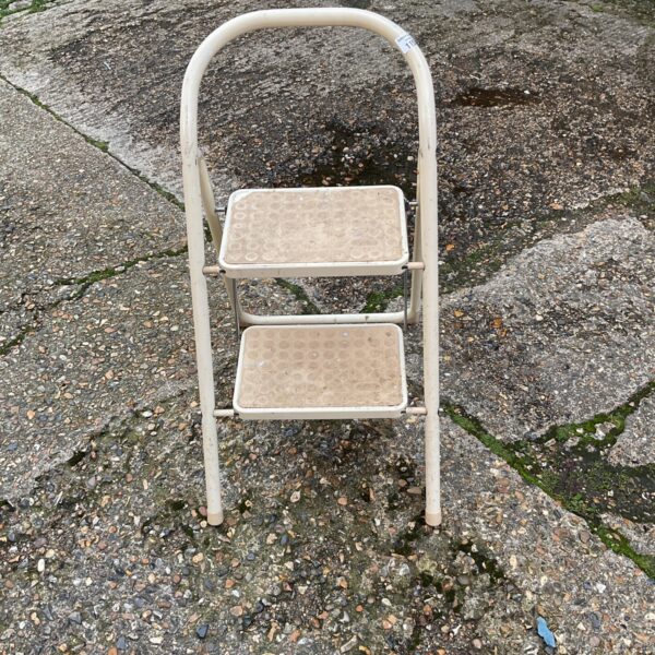 Vintage kitchen step stool with enamel treads and folding design.