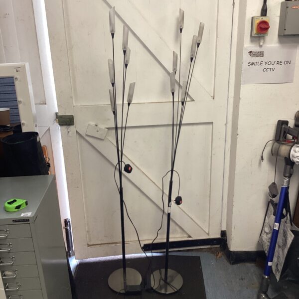 Black uplighter floor lamps with adjustable spotlights in a room.