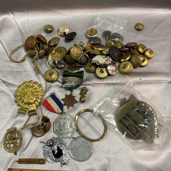 Assorted antique military buttons and badges in a collection.