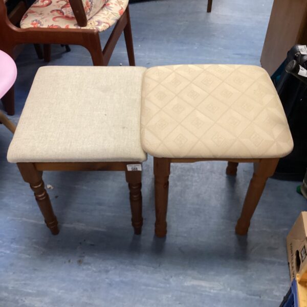 Two vintage piano stools with neutral fabric seats and wooden legs.