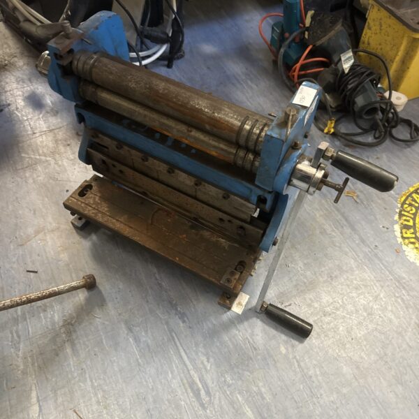 Vintage sheet metal roller for workshop use.