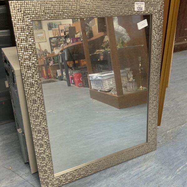 Silver bevelled wall mirror with decorative frame.