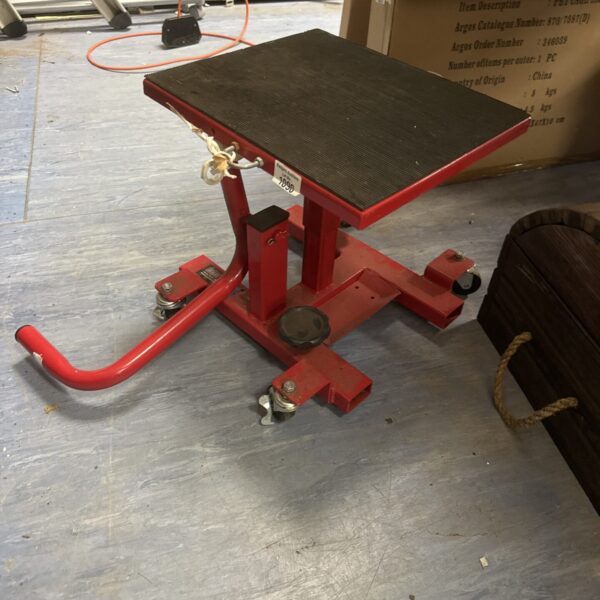 Red Sealey motorcycle lift stand for garage use.